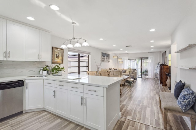 kitchen featuring sink, stainless steel dishwasher, pendant lighting, and white cabinetry