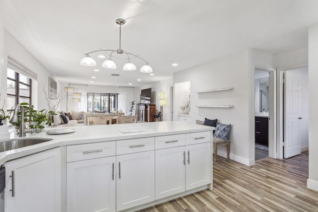 kitchen with sink, light hardwood / wood-style flooring, white cabinets, and pendant lighting