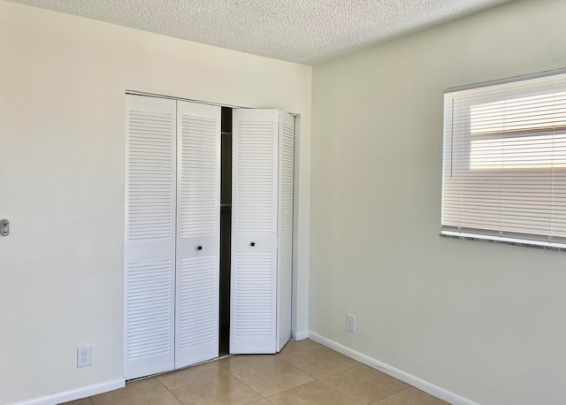 unfurnished bedroom featuring light tile patterned floors, a textured ceiling, and a closet