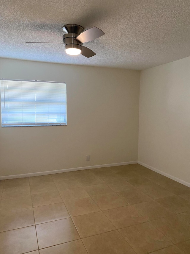 tiled empty room with ceiling fan and a textured ceiling