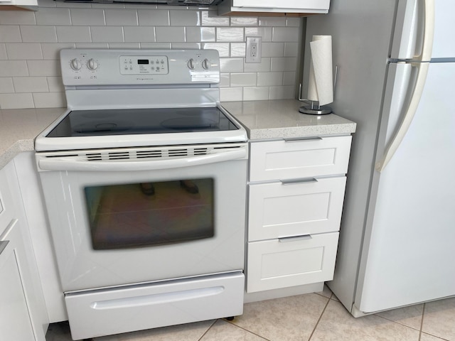 kitchen featuring decorative backsplash, stainless steel fridge, electric stove, light tile patterned floors, and white cabinets