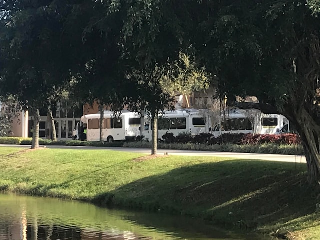 view of property's community with a lawn and a water view