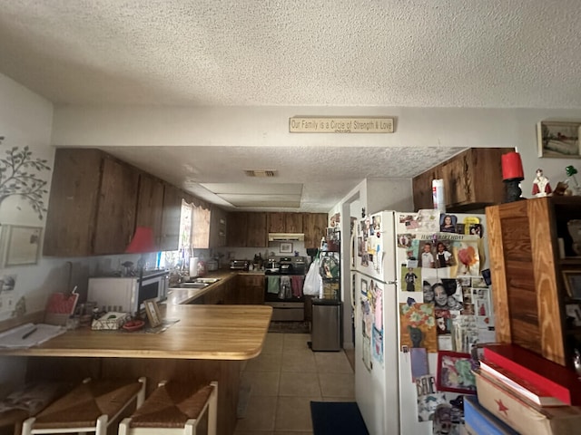 kitchen featuring kitchen peninsula, a textured ceiling, and white appliances