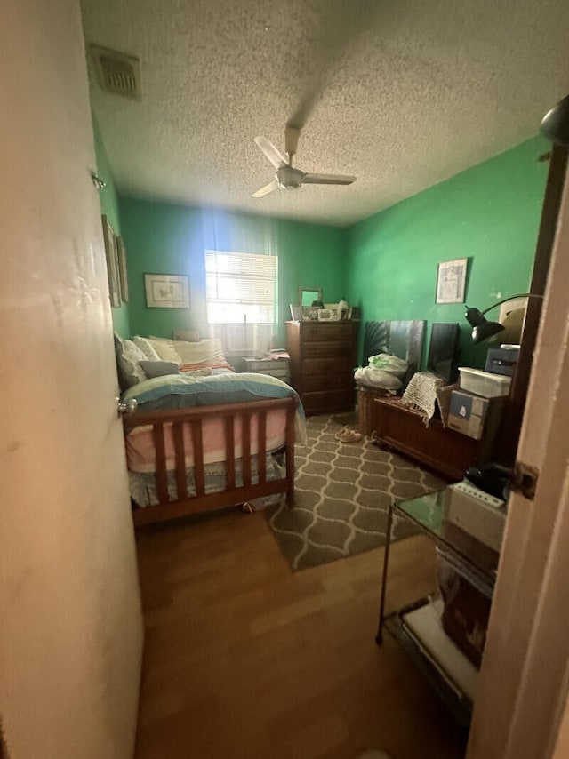 bedroom featuring a textured ceiling, ceiling fan, and dark wood-type flooring