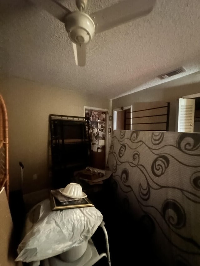 bedroom with ceiling fan and a textured ceiling