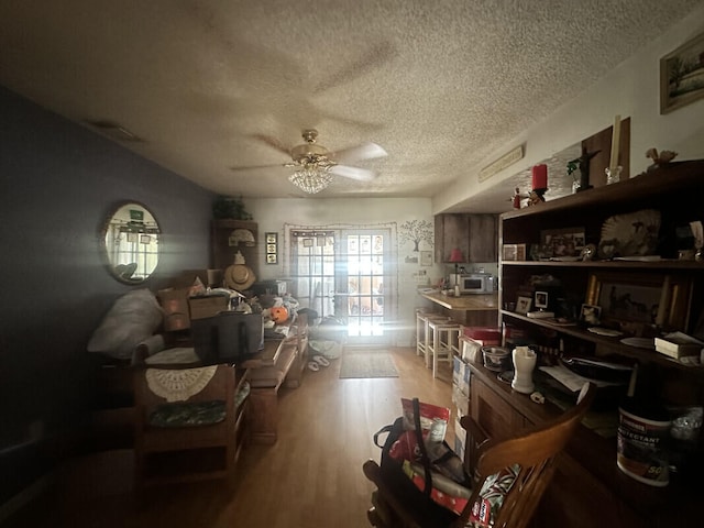 miscellaneous room featuring ceiling fan, light hardwood / wood-style floors, and a textured ceiling