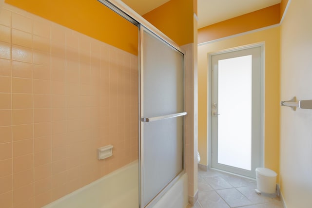 bathroom with toilet, enclosed tub / shower combo, tile patterned floors, and a healthy amount of sunlight