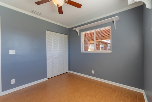 unfurnished bedroom featuring ceiling fan, a closet, hardwood / wood-style flooring, and crown molding