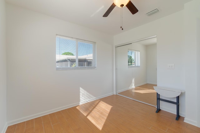 unfurnished bedroom with ceiling fan, a closet, and hardwood / wood-style flooring