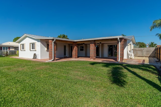 rear view of house featuring ceiling fan, a lawn, and a patio