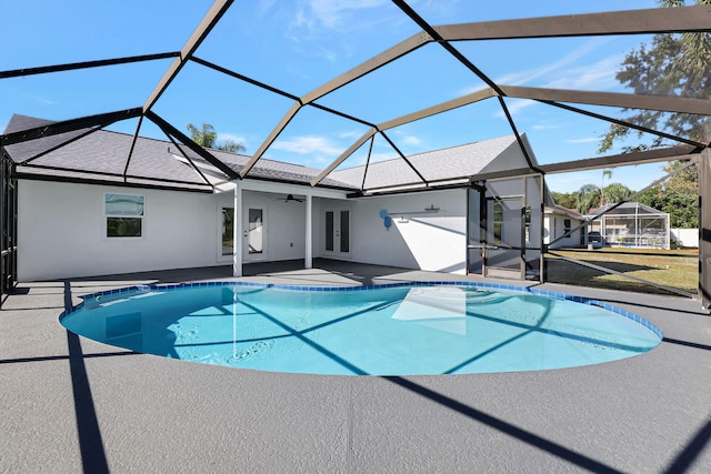 view of swimming pool with glass enclosure, ceiling fan, and a patio area