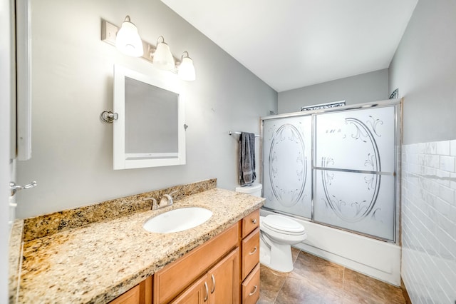 full bathroom featuring tile patterned flooring, enclosed tub / shower combo, toilet, vanity, and tile walls