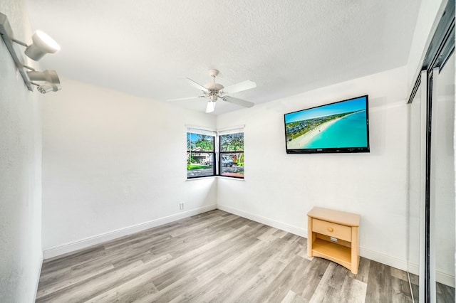 unfurnished room featuring a textured ceiling, light hardwood / wood-style flooring, and ceiling fan