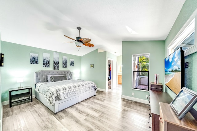 bedroom with light hardwood / wood-style floors, a spacious closet, ceiling fan, and lofted ceiling