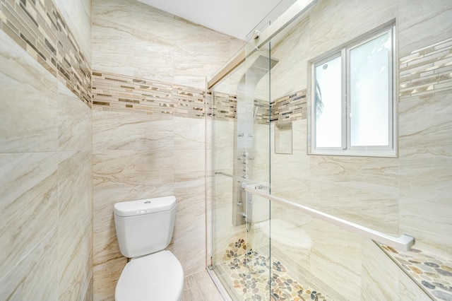 bathroom featuring a shower with door, tile walls, and toilet