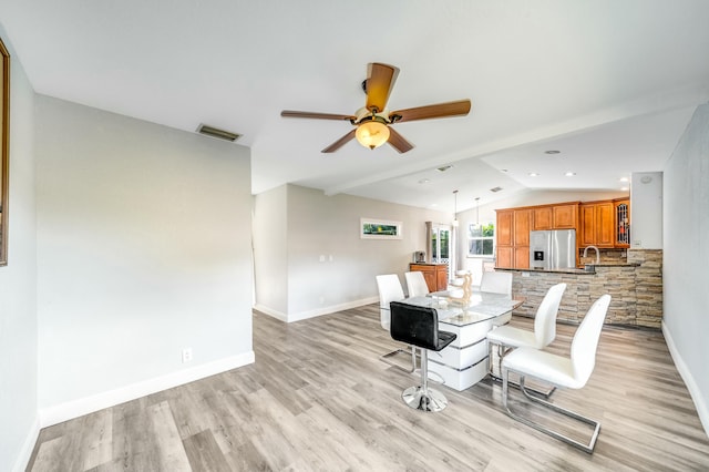 dining room with ceiling fan, vaulted ceiling, sink, and light hardwood / wood-style flooring