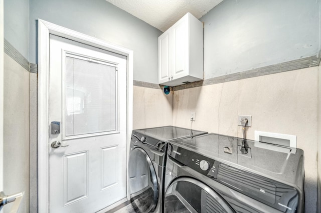 washroom featuring washer and dryer, a textured ceiling, and cabinets