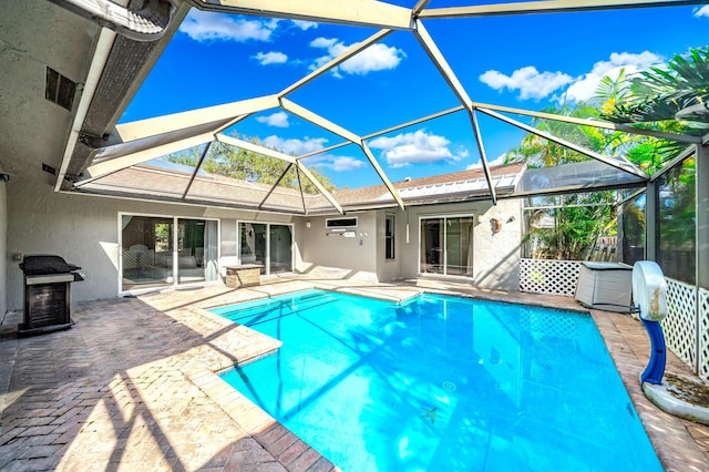 view of swimming pool featuring area for grilling, glass enclosure, and a patio area