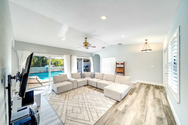 living room with ceiling fan, light wood-type flooring, and lofted ceiling