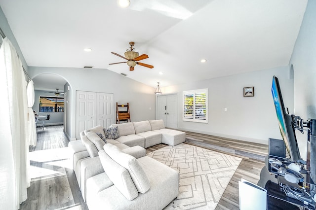 living room with ceiling fan, light wood-type flooring, and vaulted ceiling