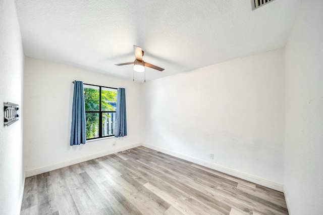 spare room featuring a textured ceiling, light wood-type flooring, and ceiling fan