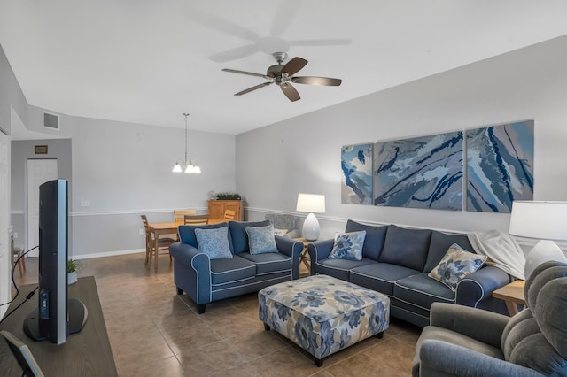 living room with ceiling fan with notable chandelier and dark tile patterned floors