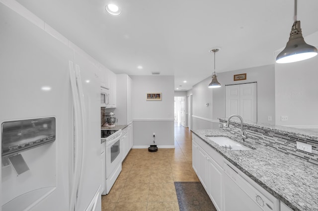 kitchen with backsplash, light stone counters, white appliances, sink, and white cabinetry