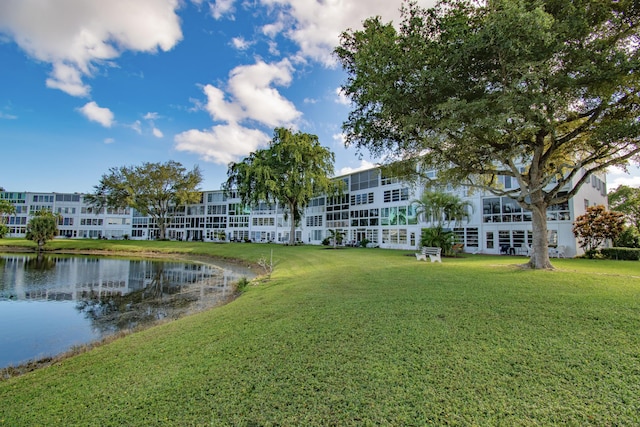 surrounding community with a water view and a yard