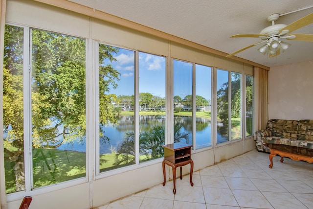 sunroom featuring ceiling fan and a water view