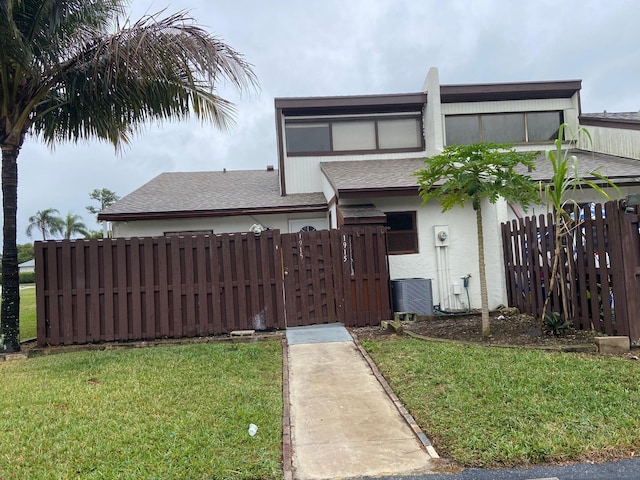 view of front of home with a front yard and central air condition unit