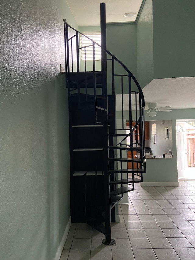 staircase with ceiling fan and tile patterned floors