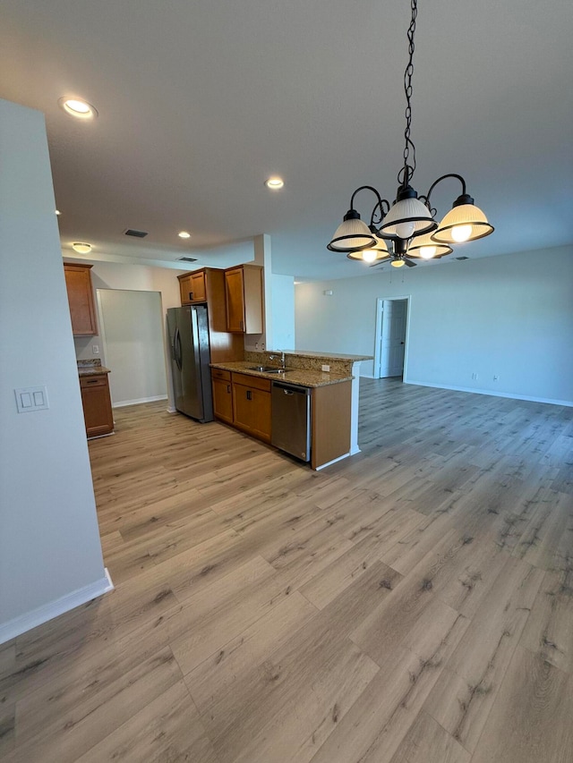 kitchen featuring stone counters, hanging light fixtures, light hardwood / wood-style flooring, appliances with stainless steel finishes, and a chandelier