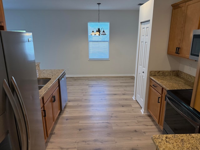 kitchen featuring an inviting chandelier, hanging light fixtures, light stone countertops, light wood-type flooring, and stainless steel appliances