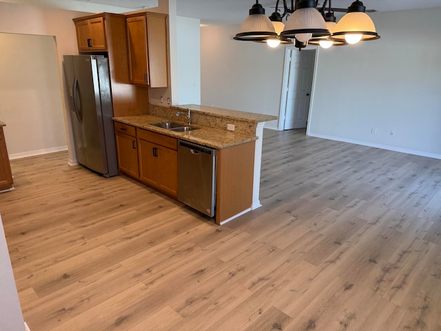 kitchen with sink, light hardwood / wood-style flooring, appliances with stainless steel finishes, a notable chandelier, and light stone counters