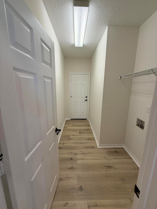 hall featuring light hardwood / wood-style flooring and a textured ceiling