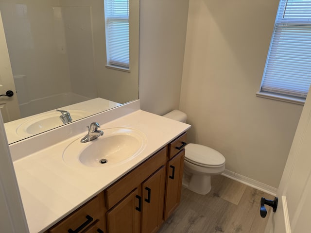 bathroom featuring plenty of natural light, vanity, hardwood / wood-style floors, and toilet