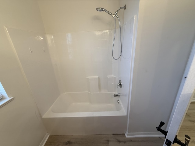 bathroom with hardwood / wood-style floors and washtub / shower combination