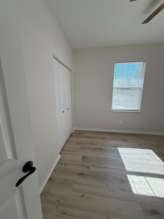 unfurnished bedroom featuring a closet, light hardwood / wood-style floors, and ceiling fan