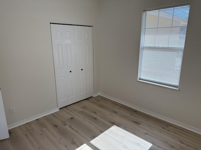 unfurnished bedroom featuring light hardwood / wood-style flooring and a closet