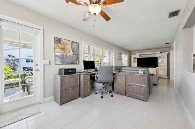 home office with a textured ceiling, ceiling fan, and light tile patterned flooring