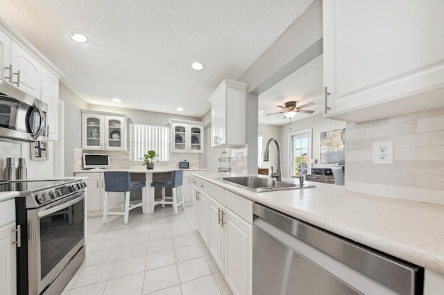 kitchen with backsplash, white cabinets, sink, ceiling fan, and stainless steel appliances