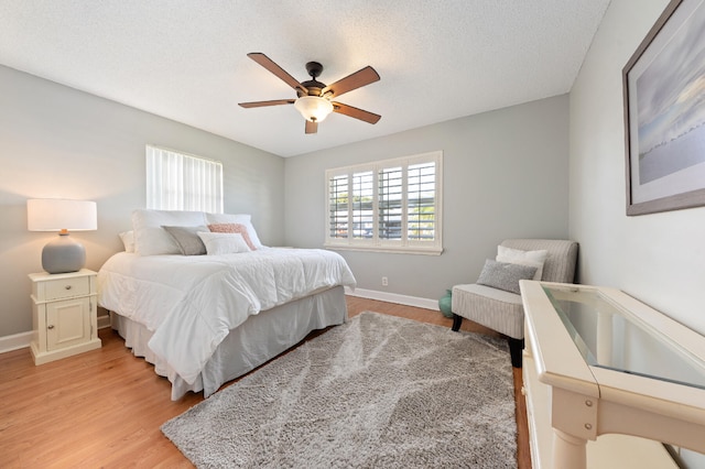 bedroom with ceiling fan, light wood-type flooring, and a textured ceiling