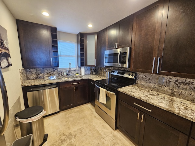 kitchen featuring light stone counters, decorative backsplash, stainless steel appliances, and a sink