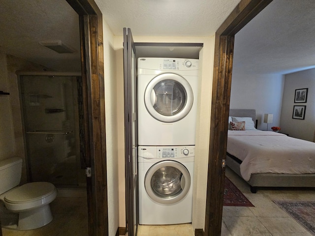 laundry area featuring a textured ceiling and stacked washer / drying machine