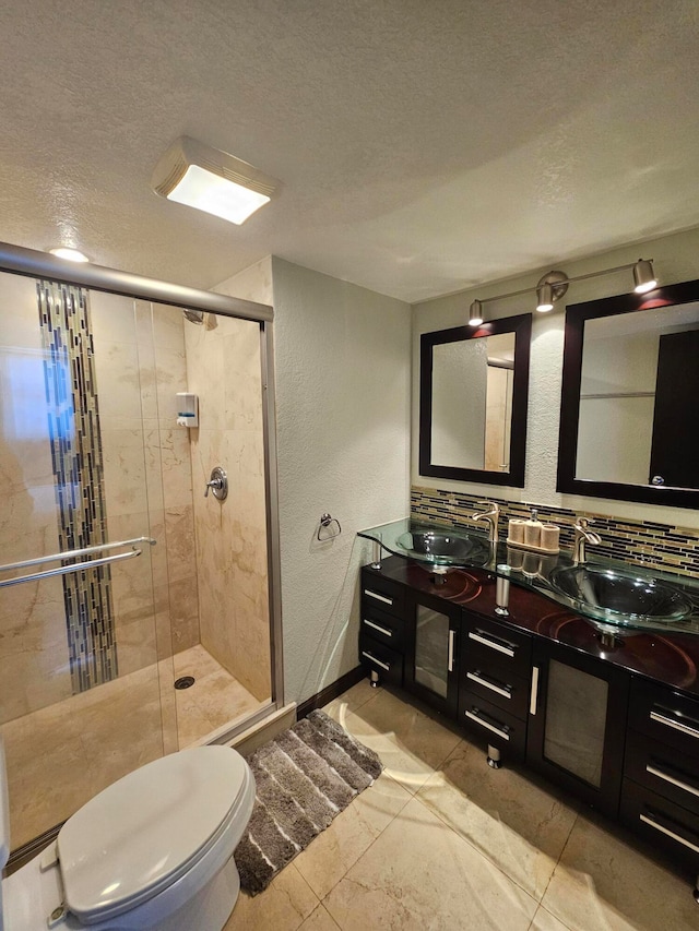 bathroom with vanity, toilet, a shower with door, and a textured ceiling