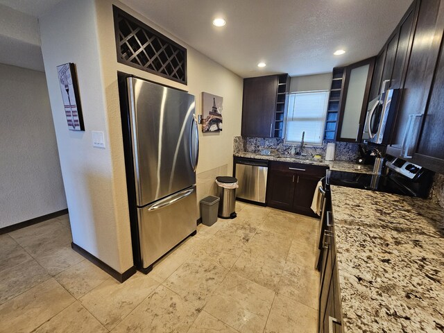 kitchen featuring light stone counters, sink, dark brown cabinets, and stainless steel appliances