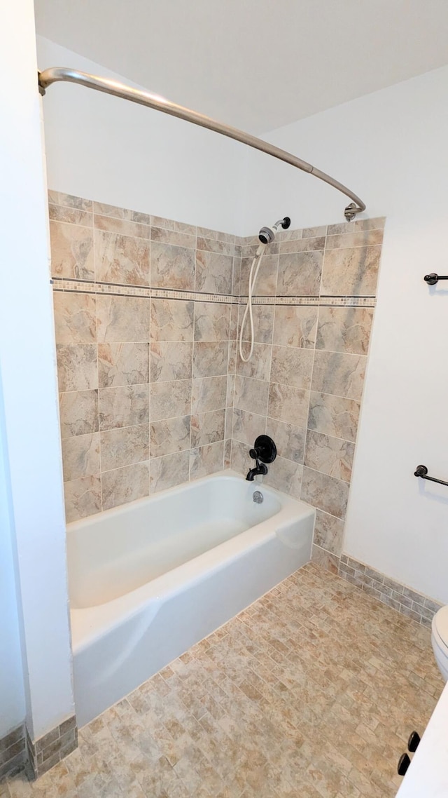 bathroom featuring toilet and tiled shower / bath