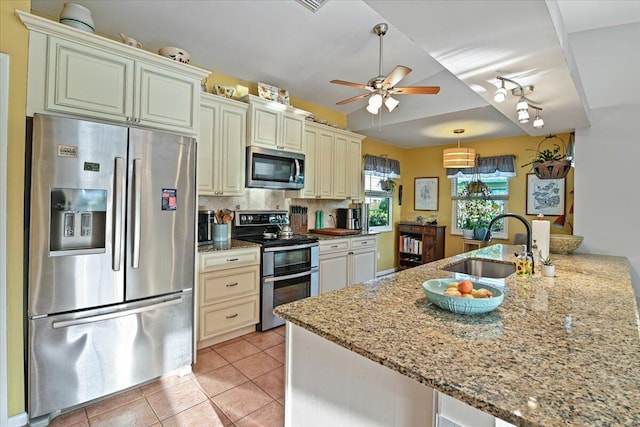 kitchen featuring cream cabinetry, stainless steel appliances, light stone countertops, and sink