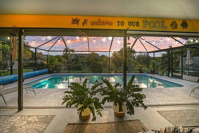 pool at dusk with a lanai and a patio