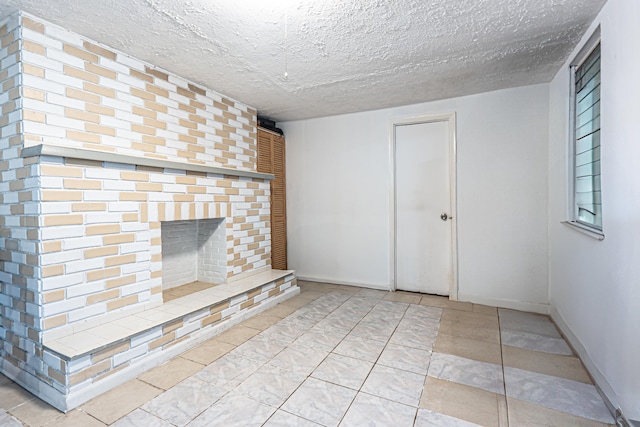 unfurnished living room featuring a fireplace, light tile patterned floors, and a textured ceiling